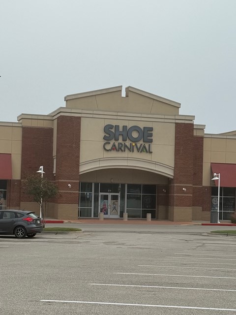Shoe Carnival storefront with a car parked in front.