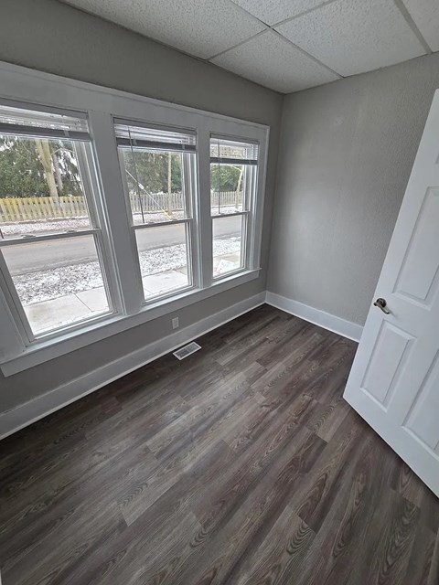 A room with a white door and a window with a view of a street.