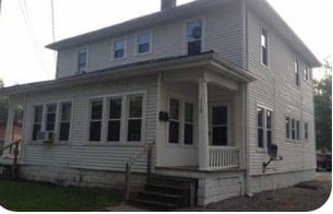 A white house with a porch and a black door.