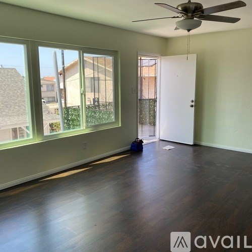 A room with a ceiling fan and a window overlooking a building.