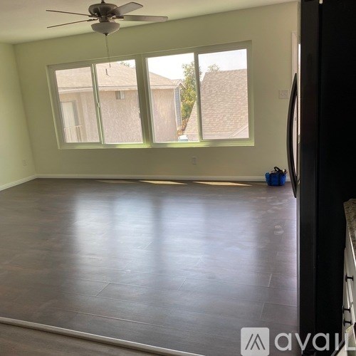A room with a ceiling fan and a large window.