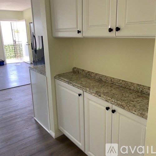 A kitchen with white cabinets and a granite countertop.