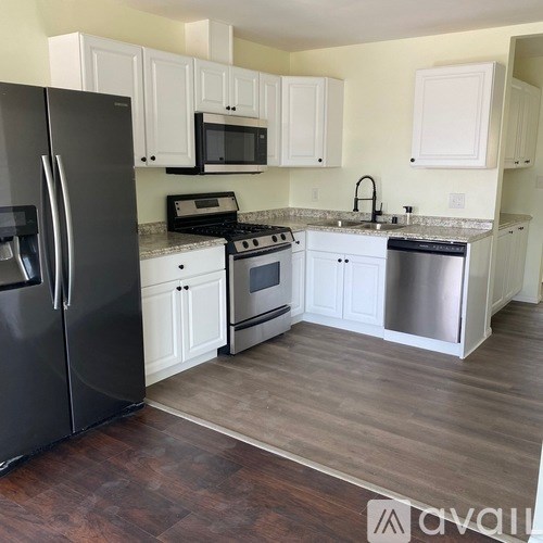 A kitchen with white cabinets and a black refrigerator.
