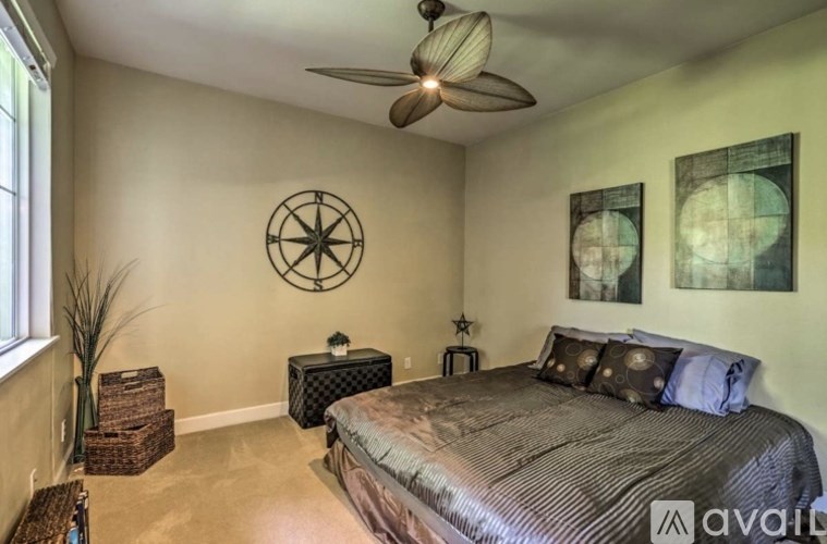 A bedroom with a bed, a ceiling fan, and a wall decoration.