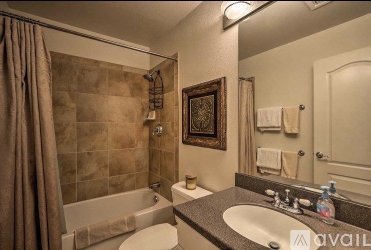 A bathroom with a brown tiled shower and a white toilet.