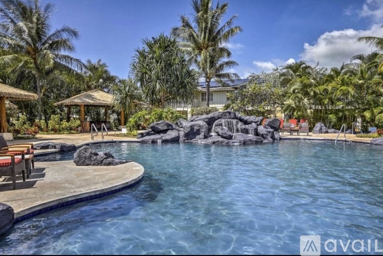 A pool surrounded by palm trees and rocks.