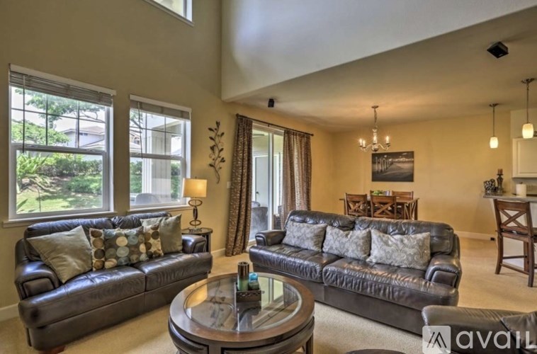 A living room with a black leather couch and a glass coffee table.