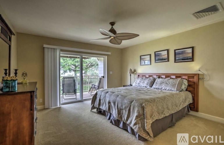 A bedroom with a bed, a dresser, and a ceiling fan.