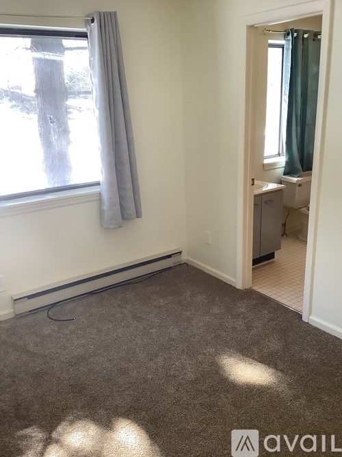 A room with a window and a carpeted floor.