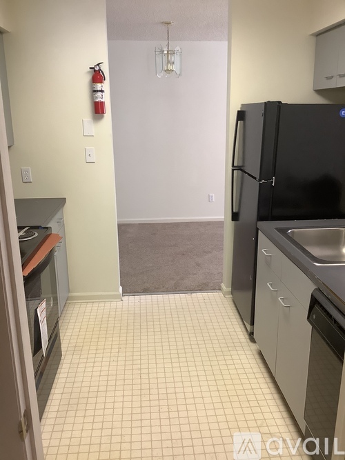 A kitchen with a black fridge and a fire extinguisher on the wall.