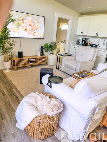 A living room with a white couch and a painting on the wall.