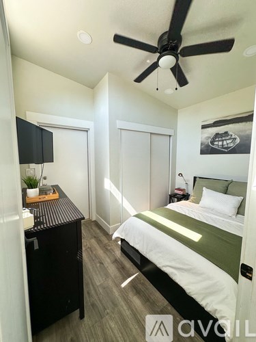 A bedroom with a bed, a ceiling fan, and a television.