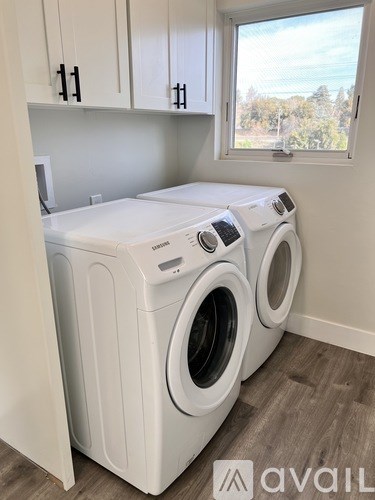 A white front loading washing machine and dryer in a laundry room.
