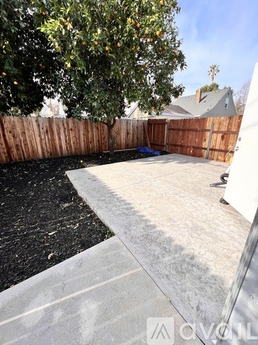 A backyard with a concrete patio and a lemon tree.
