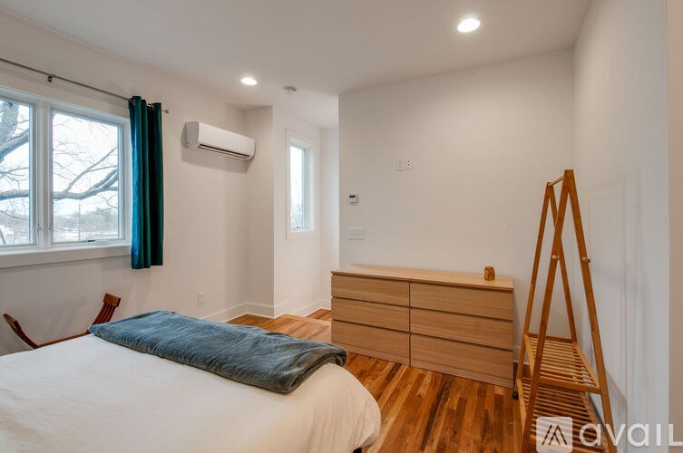 A bedroom with a bed, a chair, and a wooden dresser.