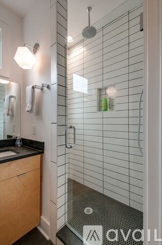 A shower area with a glass door and a tiled wall.