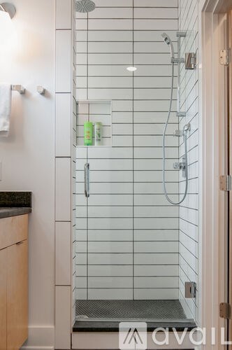 A white tiled shower with a glass door and a step in.