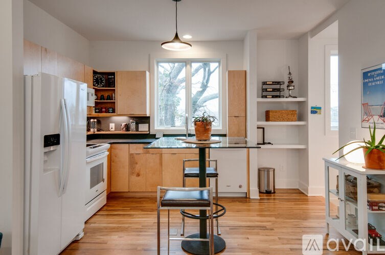 A kitchen with white appliances and wooden floors.