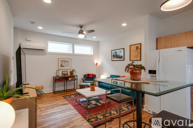 A living room with a glass table and a rug on the floor.