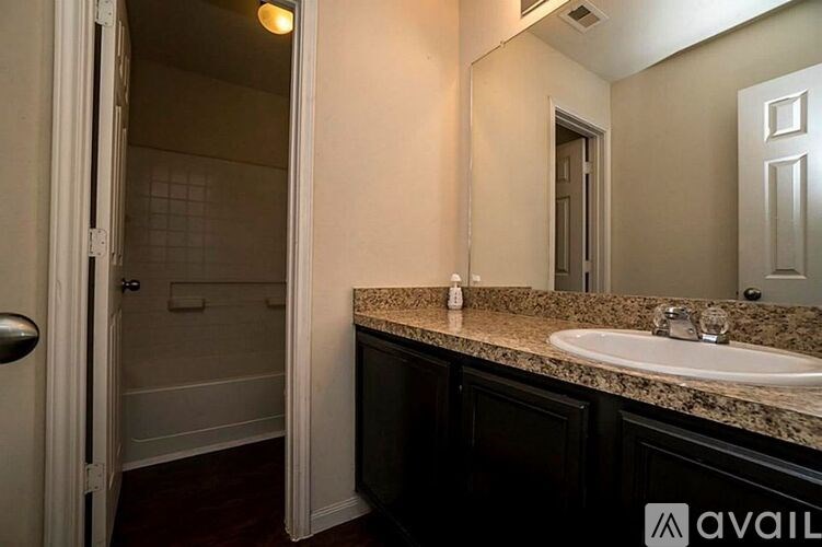 A bathroom with a sink, mirror, and a shower.