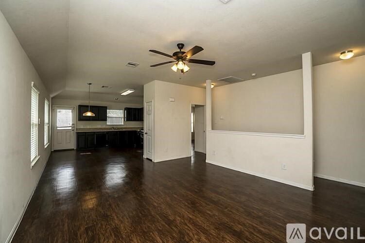 A spacious room with a ceiling fan and hardwood floors.