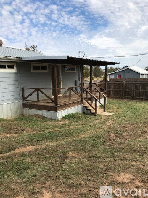 A small house with a porch and a fence in the yard.