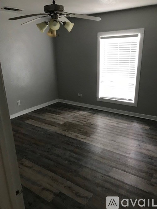 A room with a ceiling fan and a window with blinds.