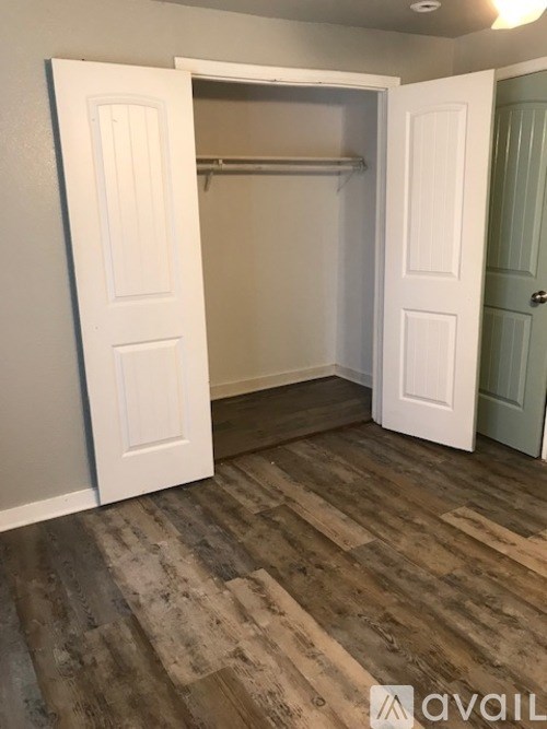 A room with a white door and a wooden floor.