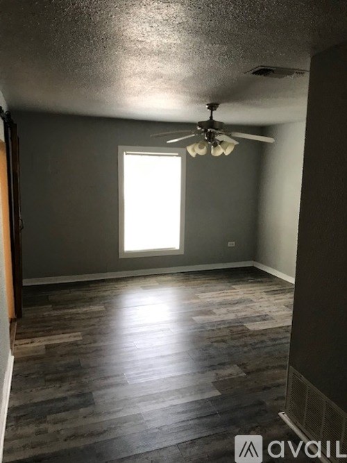A room with a ceiling fan and a window letting in light.
