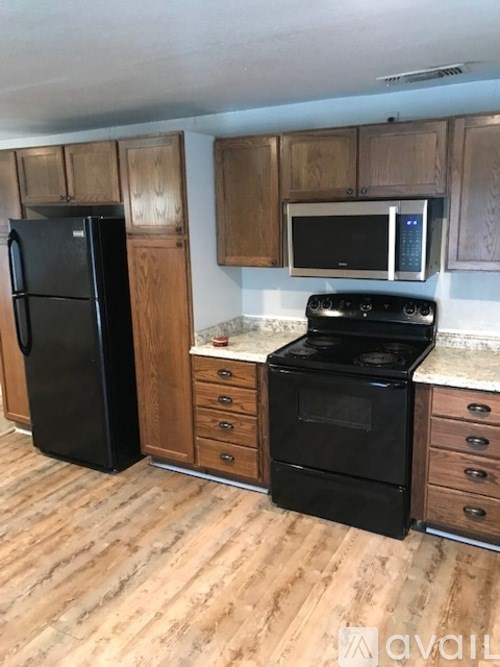A kitchen with black appliances and wooden cabinets.