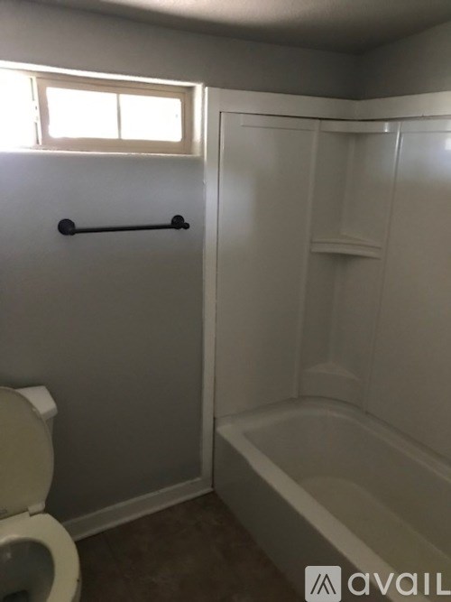 A bathroom with a toilet, tub, and window.