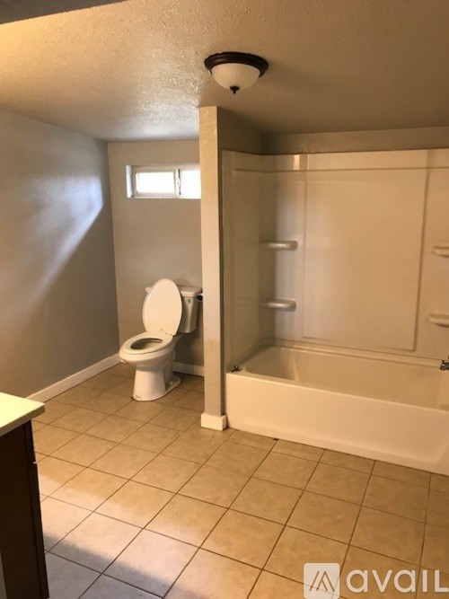 A bathroom with a toilet, tub, and a window.