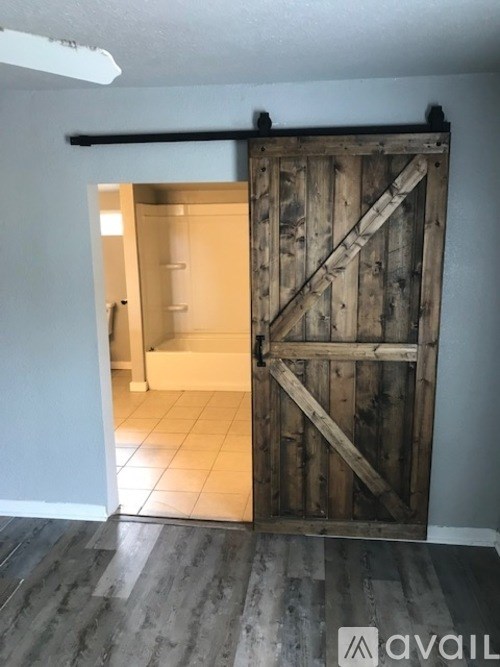 A large wooden door is open to a small room.