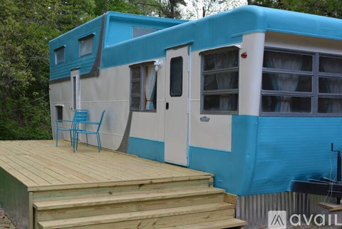 A blue and white house with a wooden deck and a blue chair.
