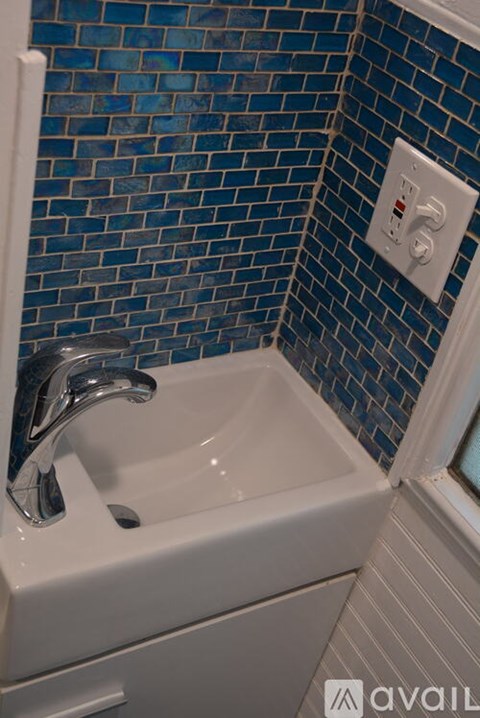 A white sink with a silver faucet in a blue tiled bathroom.