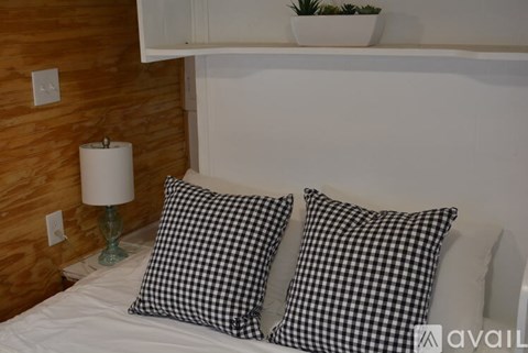 A bed with two black and white pillows and a green lamp.
