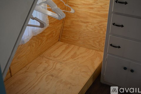 A wooden floor with a white cabinet and a hanger on it.