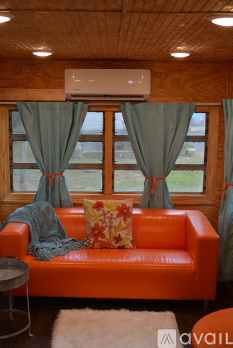 A living room with an orange couch and a window with curtains.