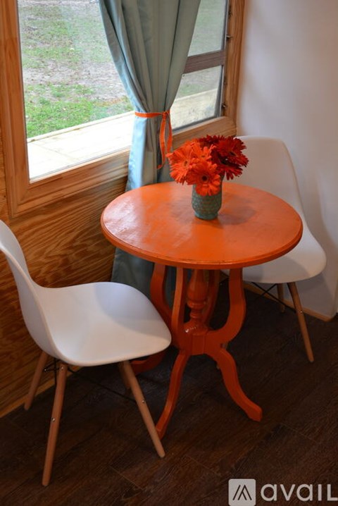 A table with a vase of flowers on it and two chairs.