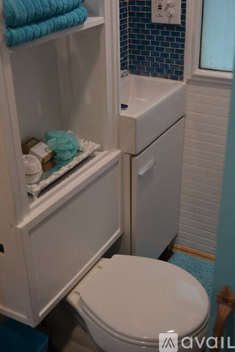 A white toilet with a white cabinet above it and a blue tiled wall behind it.