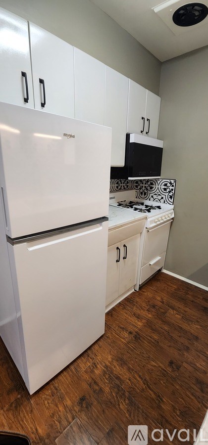 A white refrigerator in a kitchen with wooden floors.