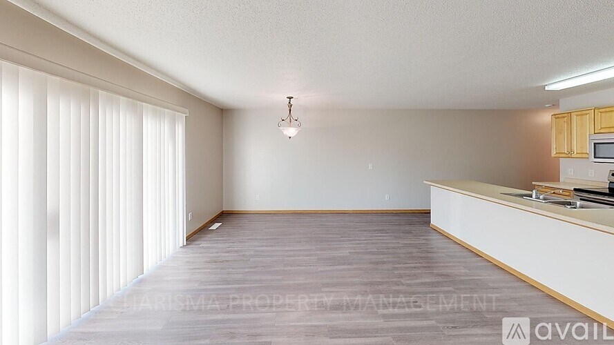 A room with a wooden floor and a window with blinds.