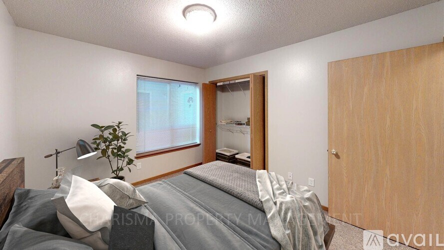 A bedroom with a bed, a plant, and a mirror.