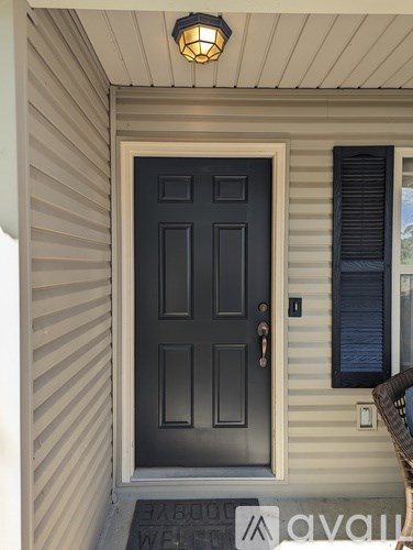 A black door with a silver handle is on a house with a light on the ceiling.