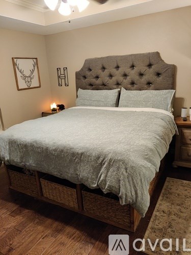 A bed with a tufted headboard and a grey bedspread is in the image.