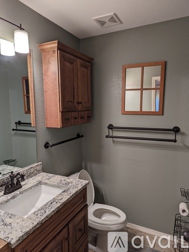 A bathroom with a toilet, sink, and wooden cabinets.