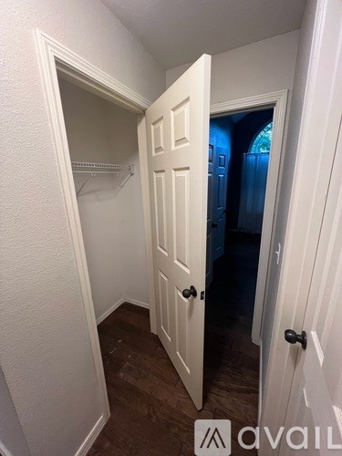 A white door with a black handle is open to a dark room.