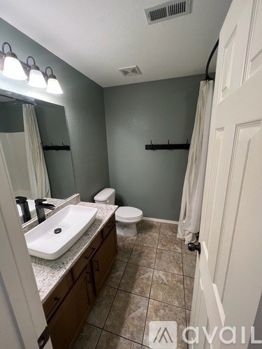 A bathroom with a sink, toilet, and mirror.