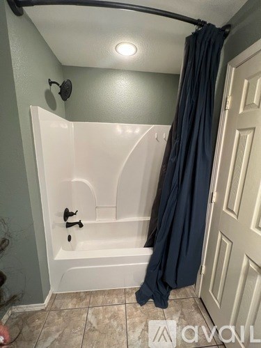 A bathroom with a white tub and a grey shower curtain.