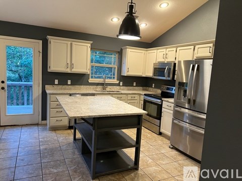 A kitchen with a table, drawers, and a refrigerator.